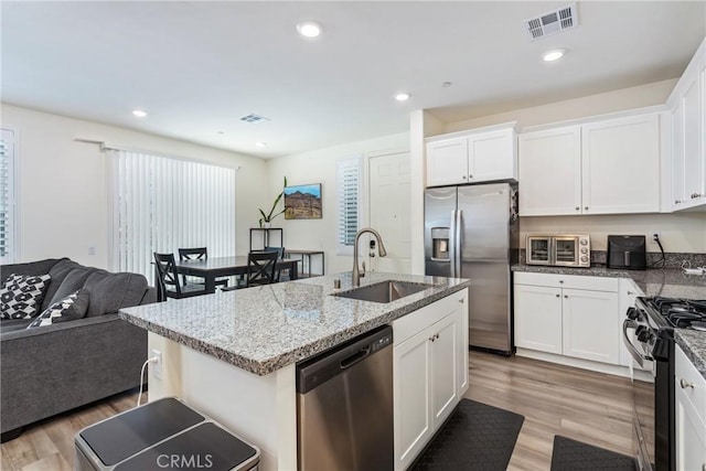 kitchen with light stone counters, visible vents, a sink, appliances with stainless steel finishes, and light wood-type flooring