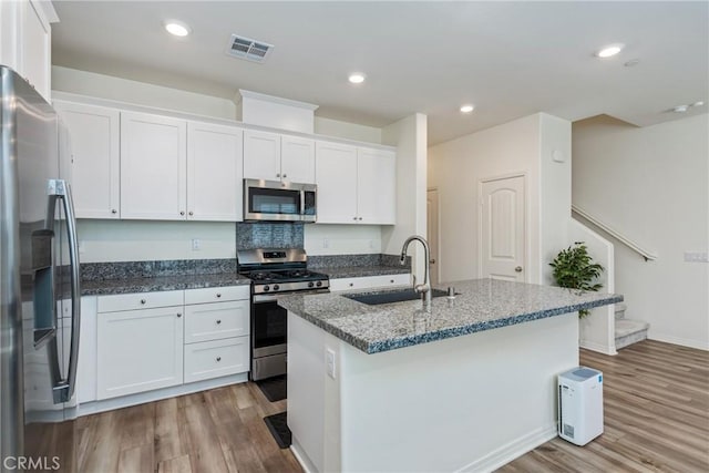 kitchen featuring wood finished floors, visible vents, a sink, white cabinets, and appliances with stainless steel finishes