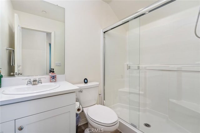 bathroom featuring toilet, a stall shower, and vanity