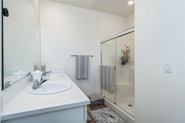 bathroom featuring a shower stall, double vanity, and a sink