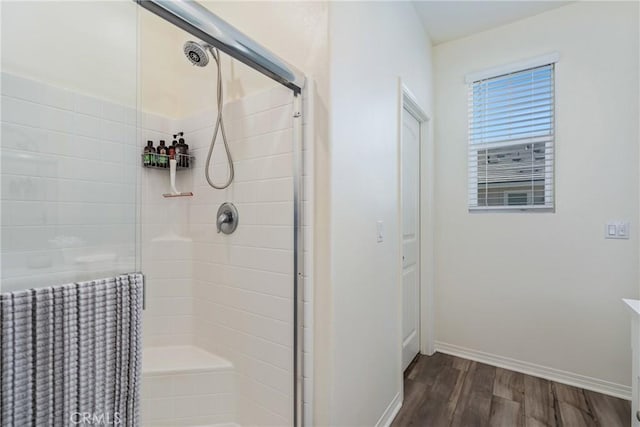 bathroom featuring a shower stall, wood finished floors, and baseboards