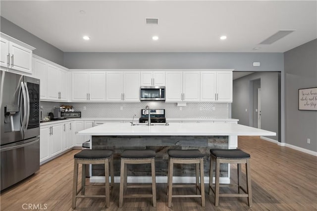 kitchen with visible vents, appliances with stainless steel finishes, white cabinets, and light wood-style flooring