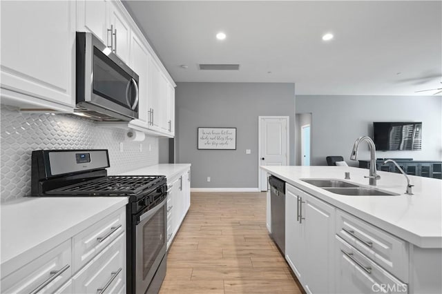 kitchen with visible vents, a sink, backsplash, stainless steel appliances, and white cabinets