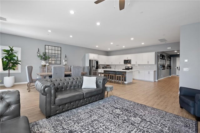 living room with recessed lighting, light wood-type flooring, baseboards, and visible vents