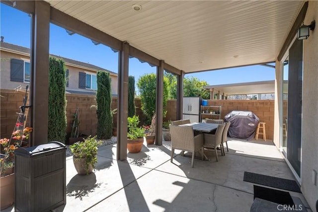 view of patio featuring outdoor dining area, grilling area, and fence