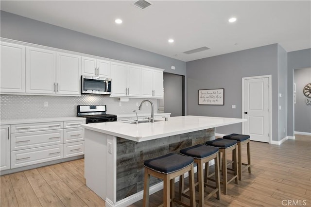 kitchen with a sink, visible vents, appliances with stainless steel finishes, and white cabinets