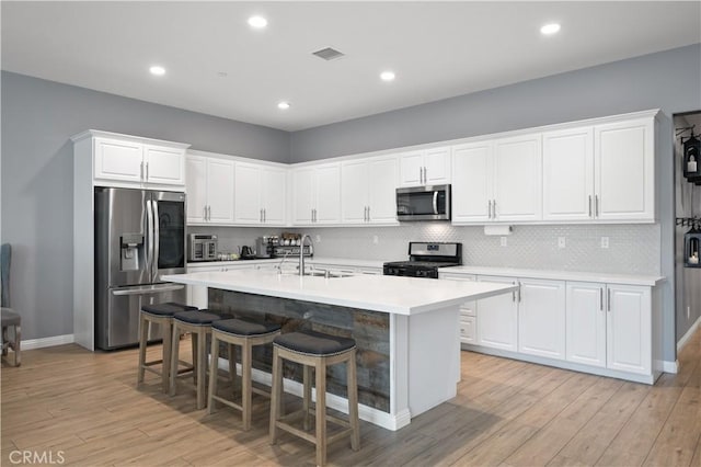 kitchen featuring visible vents, a sink, tasteful backsplash, stainless steel appliances, and light countertops