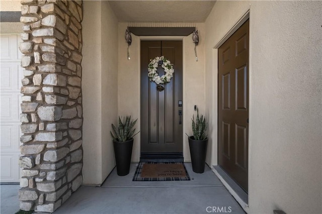 view of exterior entry featuring stone siding and stucco siding