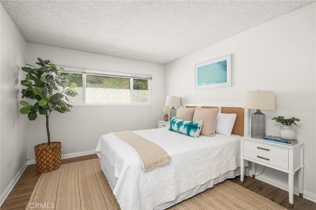 bedroom featuring baseboards, a textured ceiling, and wood finished floors