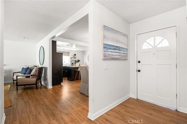 entrance foyer featuring light wood finished floors, a textured ceiling, and baseboards