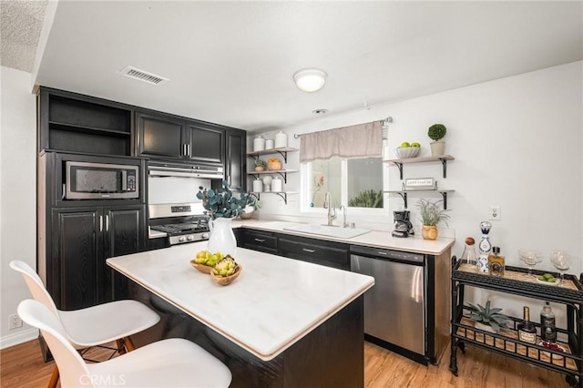 kitchen with a sink, appliances with stainless steel finishes, visible vents, and open shelves