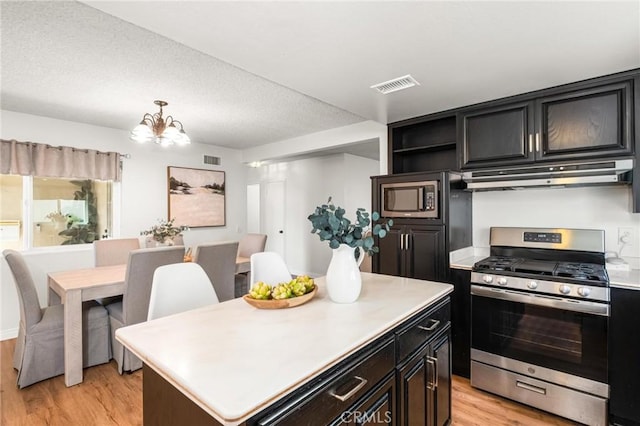 kitchen with visible vents, under cabinet range hood, stainless steel appliances, light wood finished floors, and light countertops