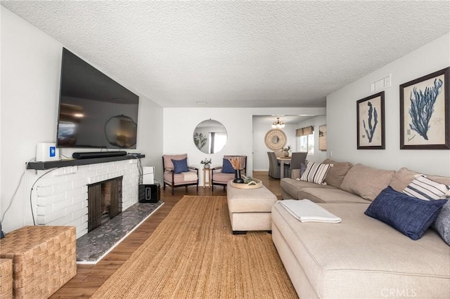 living area with visible vents, a textured ceiling, wood finished floors, and a fireplace