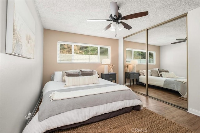 bedroom with baseboards, wood finished floors, a closet, a textured ceiling, and a ceiling fan