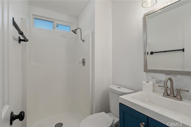 bathroom with backsplash, a stall shower, vanity, and toilet