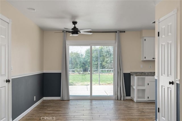 interior space featuring a ceiling fan, wood finished floors, and baseboards