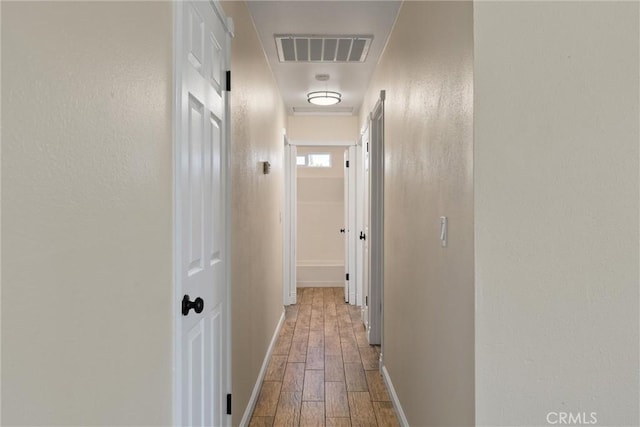 hall with wood finished floors, visible vents, and baseboards