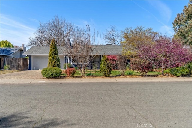 view of front of property with driveway, an attached garage, and fence