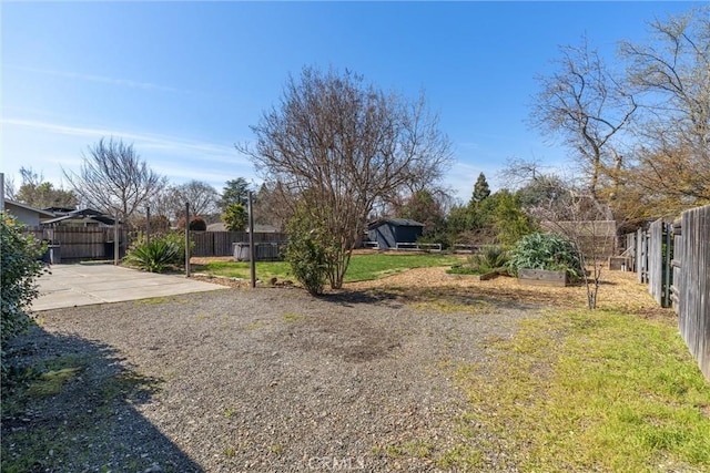 view of yard featuring a patio area, driveway, a vegetable garden, and fence