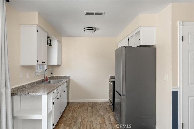 kitchen with wood finished floors, visible vents, a sink, appliances with stainless steel finishes, and white cabinetry