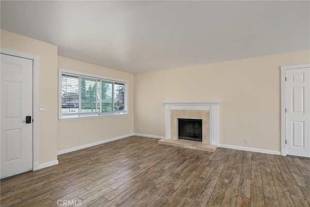 unfurnished living room featuring a fireplace, baseboards, and wood finished floors