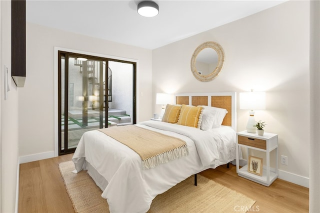 bedroom with access to exterior, light wood-style flooring, and baseboards