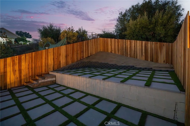 patio terrace at dusk featuring a fenced backyard