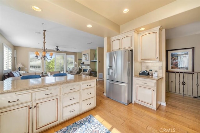 kitchen featuring open floor plan, backsplash, light wood-style floors, and stainless steel fridge with ice dispenser