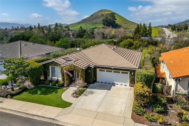 view of front of property featuring a garage, driveway, a mountain view, and a tile roof