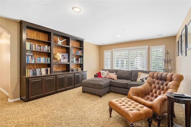 living room featuring recessed lighting, baseboards, arched walkways, and light colored carpet