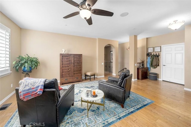 living area featuring visible vents, baseboards, wood finished floors, arched walkways, and a ceiling fan