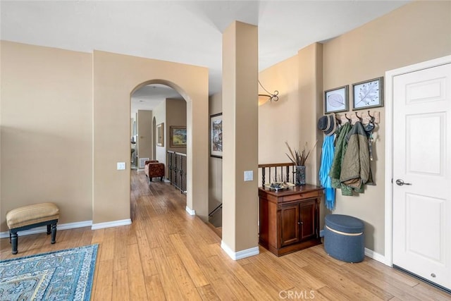 foyer with arched walkways, light wood-type flooring, and baseboards