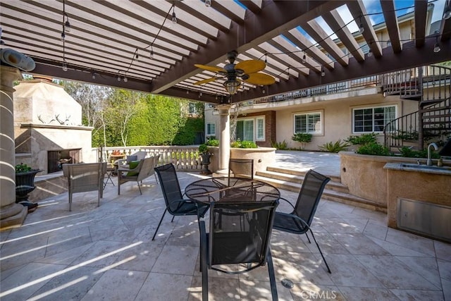 view of patio / terrace featuring a ceiling fan, outdoor dining area, a pergola, a sink, and a tile fireplace