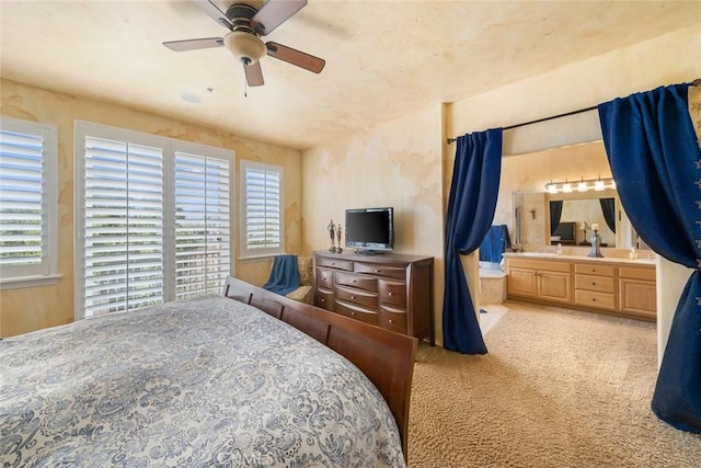 bedroom with multiple windows, a ceiling fan, light carpet, and ensuite bathroom