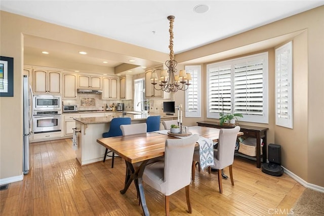 dining area with recessed lighting, light wood-style flooring, baseboards, and a chandelier