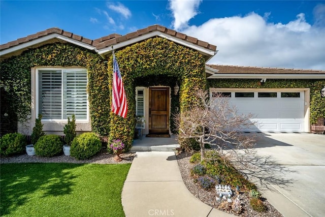 property entrance with a garage, concrete driveway, and a tiled roof