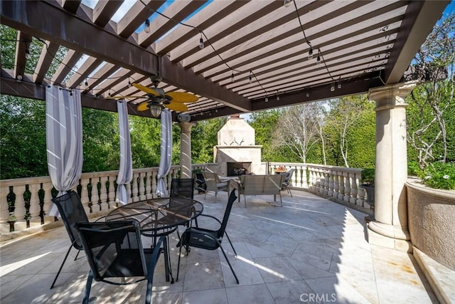 view of patio featuring exterior fireplace, outdoor dining space, a pergola, and a ceiling fan