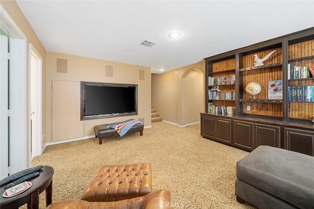 living area with visible vents, baseboards, stairway, light colored carpet, and arched walkways