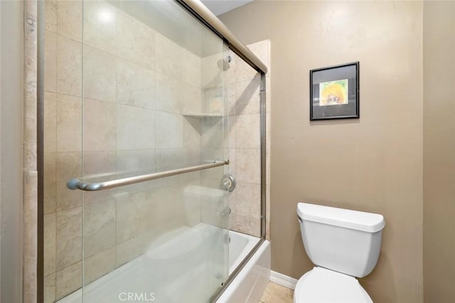 bathroom featuring baseboards, toilet, and shower / bath combination with glass door