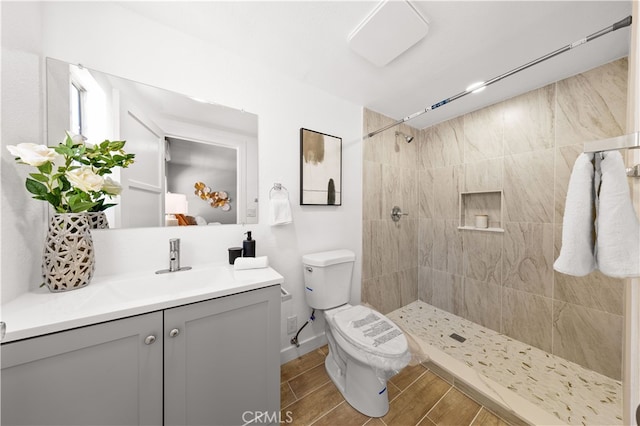 bathroom featuring vanity, wood finish floors, toilet, and tiled shower