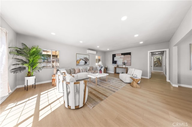 living room featuring recessed lighting, baseboards, wood finished floors, and a wall unit AC