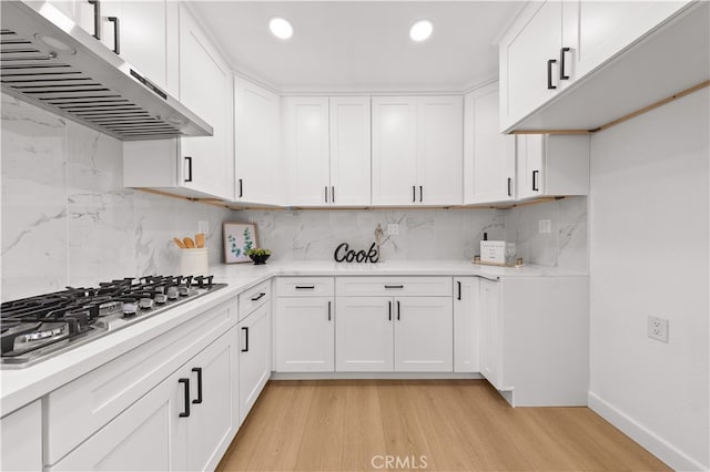 kitchen with ventilation hood, light wood-style floors, stainless steel gas stovetop, and light countertops