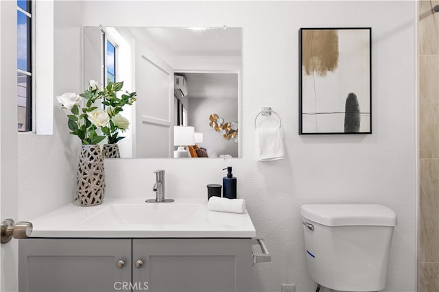 bathroom featuring toilet, vanity, and a textured wall