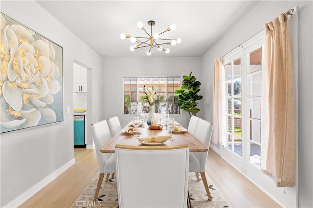 dining space featuring light wood finished floors, a notable chandelier, and baseboards