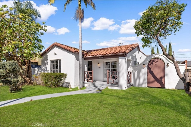 view of front of home with stucco siding, french doors, a tile roof, and a front lawn