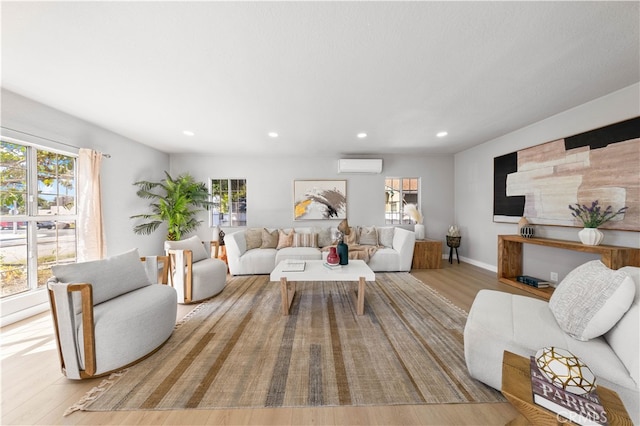 living area featuring a wall mounted air conditioner, baseboards, wood finished floors, and recessed lighting