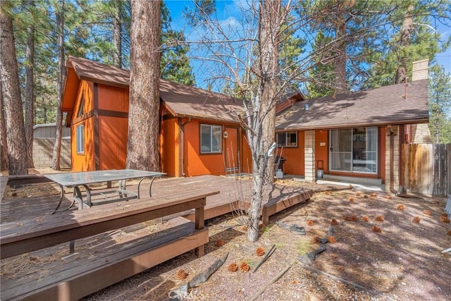 back of property with fence, a chimney, and a wooden deck