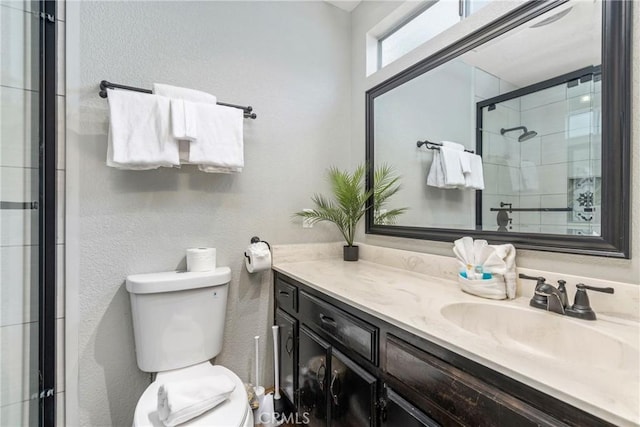 bathroom with toilet, a stall shower, and vanity