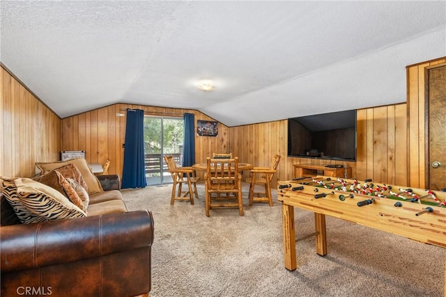 recreation room with wood walls, a textured ceiling, lofted ceiling, and carpet floors