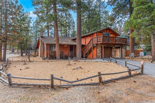 chalet / cabin with aphalt driveway, an attached garage, fence, and stone siding